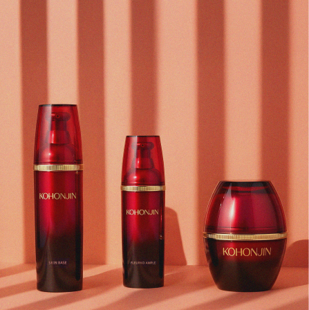 Three red skincare products with gold accents on a striped background